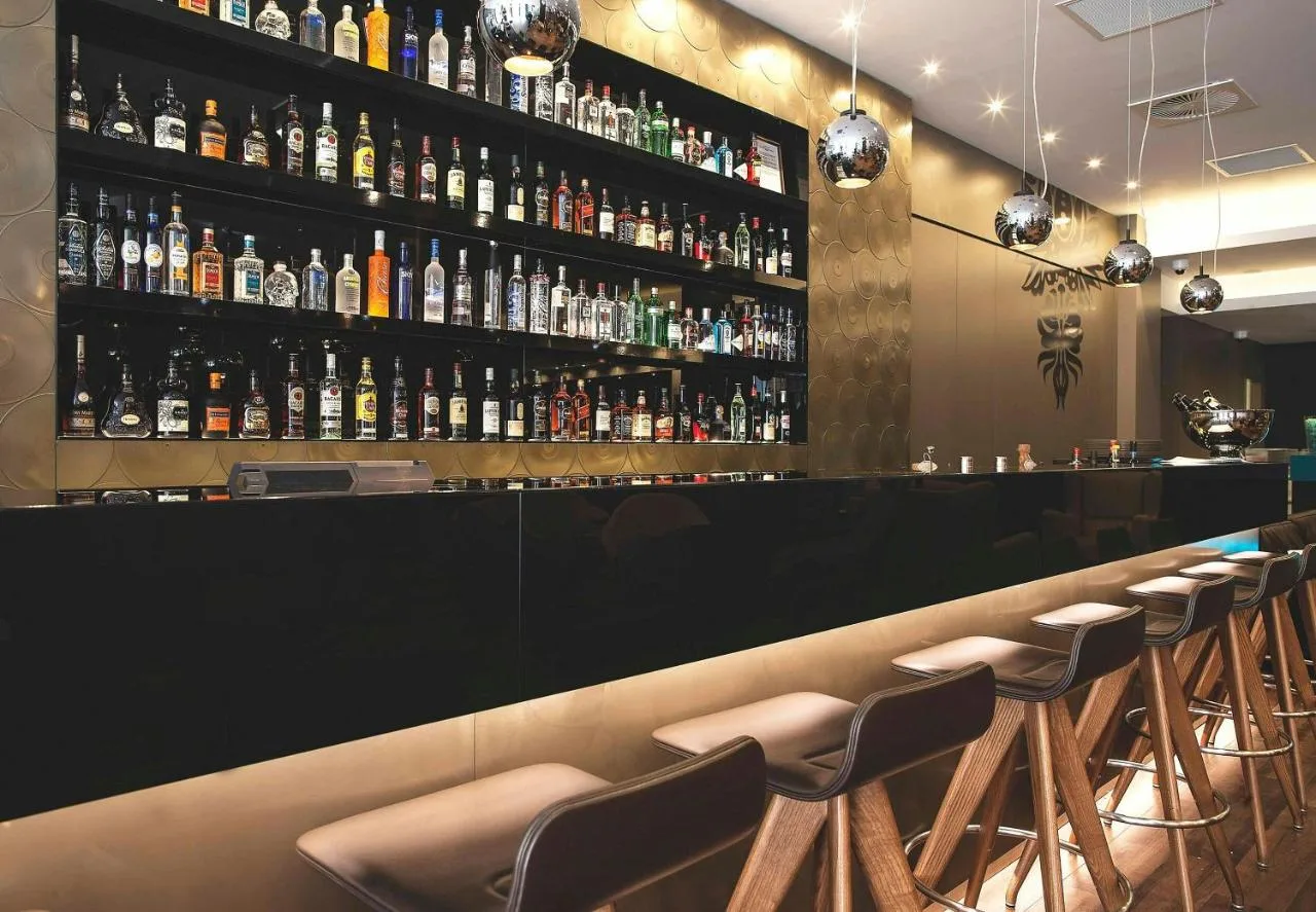 a bar with a row of stools and bottles of alcohol at Motel One Manchester-Piccadilly in Manchester